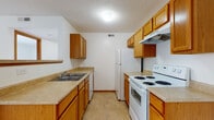 Located at 5222 Flower Valley Dr in Canal Winchester, Ohio, this single-floor unit offers a practical and comfortable layout designed for everyday living. The kitchen is well-equipped with warm oak cabinetry lining both walls, generous counter space with light-toned laminate surfaces, and white appliances including a coil-burner electric range, a dishwasher, and a full-size refrigerator. Tile flooring and an overhead range hood add to the kitchen's functional character. The full bathroom features a wood-trimmed vanity with a single sink, tile flooring, and a full tub-shower combination set against clean white walls. The living area is open and inviting, with soft wall-to-wall carpeting, a large sliding glass door framed by vertical blinds that allows natural light to fill the space, and a staircase railing detail that adds visual interest. An additional open living or dining area connects to the kitchen via a raised breakfast bar, with a pendant light overhead and direct access to closet storage. The bedrooms are bright and spacious, each featuring plush carpeting and windows with blinds that bring in natural light. Throughout the unit, neutral tones, warm wood trim, and clean white walls create a cohesive, move-in ready atmosphere.