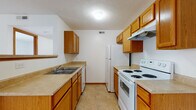 Located at 5222 Flower Valley Dr in Canal Winchester, Ohio, this single-floor unit offers a practical and comfortable layout designed for everyday living. The kitchen is well-equipped with warm oak cabinetry lining both walls, generous counter space with light-toned laminate surfaces, and white appliances including a coil-burner electric range, a dishwasher, and a full-size refrigerator. Tile flooring and an overhead range hood add to the kitchen's functional character. The full bathroom features a wood-trimmed vanity with a single sink, tile flooring, and a full tub-shower combination set against clean white walls. The living area is open and inviting, with soft wall-to-wall carpeting, a large sliding glass door framed by vertical blinds that allows natural light to fill the space, and a staircase railing detail that adds visual interest. An additional open living or dining area connects to the kitchen via a raised breakfast bar, with a pendant light overhead and direct access to closet storage. The bedrooms are bright and spacious, each featuring plush carpeting and windows with blinds that bring in natural light. Throughout the unit, neutral tones, warm wood trim, and clean white walls create a cohesive, move-in ready atmosphere.