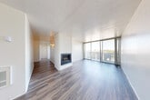 Located at 1405 Marshall in Redwood City, CA, this well-appointed one-bedroom, two-bathroom unit offers a thoughtfully designed single-floor layout with generous living space. The open living area is a standout, anchored by a striking white brick fireplace that rises to the ceiling, adding a classic architectural focal point. Floor-to-ceiling windows and sliding glass doors flood the room with natural light and provide direct access to a private balcony with open outdoor views. Wood-style flooring flows consistently throughout the unit, lending warmth and cohesion to every room. The galley-style kitchen features white cabinetry, light countertops, a stainless steel sink, a dishwasher, and full appliances including a refrigerator and range. A dedicated closet off the kitchen provides additional storage. The spacious bedroom is bright and airy, benefiting from large windows that frame outdoor views. Both bathrooms are finished in clean, neutral tones with tub-shower combinations, wood-style flooring, and white vanities. A separate closet adds practical storage to the layout. The overall ambiance is clean, bright, and move-in ready, making this Redwood City unit an inviting and functional living space.