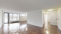 This single-floor residence offers a thoughtfully designed layout that balances open living spaces with functional private areas. Throughout the unit, rich parquet hardwood flooring adds warmth and character, reflecting natural light that streams in through wide horizontal windows fitted with blinds. The spacious living and dining areas are defined by clean white walls and a textured ceiling, creating a bright, neutral backdrop ideal for any décor style. Large windows along the exterior walls provide generous daylighting and views of surrounding greenery, while a baseboard heating unit ensures year-round comfort. The kitchen has been updated with crisp white shaker-style cabinetry, granite countertops with subtle grey and white veining, a subway tile backsplash, a stainless steel sink with a pull-down faucet, and a stainless steel dishwasher. Light-toned tile flooring completes the kitchen's clean, modern aesthetic. The bedroom is a well-proportioned, quiet retreat, also featuring parquet floors and ample wall space. The bathroom is finished in an all-white palette with tile flooring, a combined tub and shower with a curved curtain rod, a vanity with under-sink storage, and a toilet — offering a clean, functional design. A hallway connects the private rooms, providing an organized and practical flow throughout the unit.