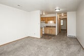 This single-floor space offers a practical and straightforward layout designed for comfortable everyday living. The kitchen is equipped with warm honey-toned wood cabinetry, both upper and lower storage, dark granite-style countertops, a double stainless steel sink, a white electric range with overhead ventilation, and durable tile flooring — providing a fully functional cooking space. A refrigerator is also included. The kitchen opens toward the living area, which features neutral wall-to-wall carpeting, warm wood baseboards, and a textured ceiling throughout, creating a cohesive and cozy atmosphere. The spacious living area offers generous room for furniture arrangement and flows naturally into the rest of the unit. The bedroom is well-proportioned, featuring soft carpeting underfoot, a window that allows natural light and outdoor views, and two sliding-door closets that provide substantial storage capacity. The bathroom includes a vanity with dark countertop and wood cabinetry, a full-sized soaking tub with a tiled surround and showerhead, and tile flooring. Throughout the unit, consistent finishes such as wood-trimmed doorways, textured ceilings, and neutral tones create a unified, livable aesthetic.