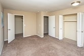 Located at 495 Coachman Dr in Troy, Michigan, this single-story unit offers a practical and well-organized layout designed for comfortable everyday living. The floor plan, visible in the 3D model, reveals a logical flow connecting the main living areas, bedrooms, hallway, and kitchen.

The living area is anchored by a full-width sliding glass door dressed with vertical blinds, allowing generous natural light and providing direct views of the surrounding greenery outside. Neutral-toned carpet grounds the space and continues throughout several of the bedrooms, each of which features windows with vertical blinds that maintain a consistent aesthetic. One bedroom showcases rich hardwood-style flooring and a ceiling fan, offering a slightly distinct character from the others. Closet storage is well-represented, with at least one bedroom featuring a walk-in closet alongside an additional standard closet.

The kitchen is efficiently designed with white shaker-style cabinetry, granite-look countertops, a stainless steel refrigerator, and a stainless electric range with an overhead ventilation hood. A dishwasher completes the appliance package, and hardwood-style flooring adds a clean, durable finish underfoot.

A hallway connects the bedroom wing to the kitchen, passing a bathroom vanity outfitted with white cabinetry, a single sink, and a well-lit mirror. The overall palette throughout is warm and neutral, creating a cohesive and move-in-ready environment.
