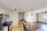 Located in the heart of downtown Edmonton at 10051 109 St NW, this well-designed one-bedroom, one-bathroom unit offers a smart and functional layout across a single floor. The open-concept living and kitchen area forms the heart of the space, where warm hardwood flooring flows seamlessly from the kitchen into the living room, creating a cohesive and inviting atmosphere.

The kitchen is a standout feature, equipped with light-toned cabinetry, a dark countertop peninsula with a double-basin sink, subway tile backsplash, and black appliances including a refrigerator, range, and built-in microwave. Stylish pendant lighting hangs above the peninsula, adding a contemporary touch, while exposed concrete columns contribute an industrial character throughout the space.

The living area benefits from natural light through a window fitted with a ceiling fan, enhancing comfort and airflow. The bedroom is a well-proportioned retreat with hardwood flooring, a window offering natural light and urban views, and access to ample closet storage — with three closets featured throughout the unit.

The bathroom is clean and functional, featuring tile flooring, a full-size soaker tub with shower, a vanity with a dark countertop, and efficient use of the available space. Two hallways connect the rooms smoothly, contributing to an organized and practical floor plan.
