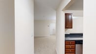 Located at 9060 Stebbing Way in Laurel, MD, this single-floor residence offers a well-organized layout designed for comfortable everyday living. The kitchen is equipped with rich cherry-toned cabinetry, dark countertops, and a full suite of stainless steel appliances, including an electric range, over-the-range microwave, and refrigerator. It connects seamlessly to the adjacent living and dining areas, which feature neutral carpeting and warm beige walls throughout.

The dining area is distinguished by a classic chandelier and chair-rail molding, lending a refined touch to the space. The living room opens directly onto a private balcony through sliding glass doors, offering pleasant views of surrounding greenery. A closet provides convenient storage near the main entry corridor.

The bedrooms are carpeted and bright, with one featuring a large window that frames lush tree views and a spacious closet. Both bathrooms are finished with rich slate-style tile flooring, cherry wood vanities with white countertops, and full soaking tub and shower combinations with brushed nickel fixtures. The overall aesthetic is clean, neutral, and move-in ready.