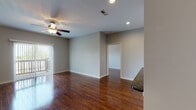 This single-floor residence offers a thoughtfully designed layout that balances open living areas with well-defined private spaces. Rich, dark hardwood flooring flows throughout the main living and bedroom areas, creating a warm and cohesive aesthetic accented by neutral gray walls and crisp white trim.

The expansive living room is bright and airy, benefiting from natural light through vertical-blind-dressed sliding doors that open to an outdoor balcony. A ceiling fan with integrated lighting adds comfort and practicality to the space. The living area connects seamlessly to a galley-style kitchen, which is equipped with stainless steel appliances including a refrigerator, range, and microwave. Warm wood cabinetry pairs elegantly with dark granite countertops, while light ceramic tile flooring completes the kitchen's clean, functional design.

A hallway with recessed lighting leads to the private quarters, where bedrooms continue the hardwood flooring theme and feature ceiling fans and windows that bring in natural light. The bathrooms are finished with dark granite-topped vanities, warm wood cabinetry, large mirrors, and tile flooring. Both bathrooms include tub-shower combinations, offering a practical yet refined finish throughout.

Overall, this residence presents a consistent design palette of quality materials and functional features that make for a comfortable, move-in-ready living environment.
