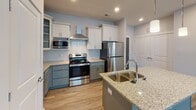 Located at 114 Apala Cir in Lynchburg, VA, this single-story home presents a clean, contemporary design throughout. The kitchen serves as a focal point of the space, showcasing a two-tone cabinet scheme with teal lower cabinets and crisp white uppers, complemented by granite countertops, a subway tile backsplash, and a full suite of stainless steel appliances including a range, microwave, and refrigerator. A central island with a double basin sink and pendant lighting above adds both functionality and visual appeal, while recessed lighting and light wood-look flooring enhance the open, airy feel.

The bedrooms feature the same durable wood-look flooring, soft neutral wall tones, and large windows fitted with blinds that allow ample natural light. At least one bedroom includes a ceiling fan for added comfort.

The bathrooms are finished with stone-look tile flooring and gray shaker-style cabinetry paired with white quartz countertops. One bathroom offers a walk-in shower, while another features a full soaking tub and shower combination with built-in shelving. Throughout the home, consistent use of neutral tones, modern fixtures, and quality finishes create a cohesive and move-in-ready living environment.