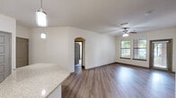 Located at 205 Verdae Blvd in Greenville, SC, this thoughtfully designed 2-bedroom, 2-bathroom residence offers a comfortable and functional single-floor layout. The open-concept kitchen and living area serve as the heart of the home, featuring rich dark cabinetry, stainless steel appliances, granite countertops, a kitchen island with pendant lighting, and track lighting overhead. Hardwood-style flooring flows through the main living areas, while ceiling fans and multiple windows invite abundant natural light.

The spacious living room is anchored by a ceiling fan and direct access to a private entrance, with large windows framing views of the surrounding greenery. An elegant arched doorway connects the living and kitchen spaces, adding a refined architectural touch.

Both bedrooms are carpeted for comfort. The primary bedroom is generously sized and features direct access to an en-suite bathroom with a tiled tub-shower combination, granite vanity, and dark cabinetry, as well as a walk-in closet outfitted with wire shelving. The second bedroom is bright and well-proportioned, with large windows offering outdoor views. Two dedicated closets and a hallway complete this well-organized floor plan.