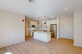 Located in Waltham, MA, this thoughtfully designed one-bedroom, one-bathroom residence offers a well-utilized single-floor layout that balances open living with functional private spaces. The heart of the home is a generous open-concept dining, kitchen, and living area finished with light hardwood-style flooring. The modern kitchen is a standout feature, boasting white shaker cabinetry, a granite-topped center island with a built-in wine cooler, stainless steel appliances including a refrigerator, range, and microwave, and stylish pendant lighting overhead. Natural light pours in through large French-style doors in the living area, creating a bright and airy atmosphere. The bedroom is carpeted for comfort and includes a natural light source via a dedicated window, while a spacious walk-in closet with built-in shelving and hanging rods provides excellent storage. The full bathroom offers a dual-sink granite vanity with white cabinetry and a large mirror. Additional highlights include a den with hardwood-style flooring, a dedicated laundry area, two closets, a utility room, and recessed lighting throughout. The neutral color palette and clean finishes give the space a fresh, contemporary feel.