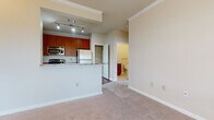 This single-floor residence offers a well-organized layout with distinct living, kitchen, sleeping, and bathroom areas. The kitchen serves as a functional centerpiece, equipped with stainless steel appliances including a refrigerator, electric range, and over-the-range microwave. Rich wood-toned cabinetry pairs with granite-look countertops, while wood-look tile flooring adds durability underfoot. A peninsula counter opens the kitchen toward the main living area, which transitions to neutral-toned carpeting at the entry point.

The living and dining area is generously proportioned, featuring crown molding, a ceiling fan, and access to an outdoor door flanked by a large window, allowing natural light to fill the space. Multiple bedrooms continue the carpeted aesthetic, each outfitted with ceiling fans and sizable windows fitted with blinds, offering views of surrounding greenery.

The bathroom is clean and practical, featuring tile flooring, a wood-cabinet vanity with a dark granite countertop, built-in shelving, and a full tub-shower combination with white tile surround. Throughout the unit, warm beige tones, white trim, and consistent finishes create a cohesive and comfortable ambiance.