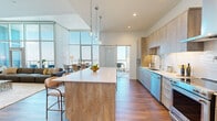 Located along the iconic Ocean Boulevard in Long Beach, California, this two-story residence offers a refined living experience across two generously sized floors. The open-concept main level seamlessly connects the kitchen, dining, and living areas, anchored by rich hardwood flooring and dramatic floor-to-ceiling windows that flood the space with natural light and frame sweeping panoramic views of the city and beyond. The chef's kitchen is appointed with warm wood cabinetry, stainless steel appliances, a pot filler, a marble-style backsplash, and a substantial waterfall-edge island with pendant lighting overhead. The dining area sits beneath soaring double-height ceilings, creating an airy, expansive atmosphere ideal for entertaining. The upper level houses the two bedrooms, including a spacious primary suite with large-format windows showcasing breathtaking elevated city views and plush carpeting underfoot. A second bedroom doubles effectively as a flexible workspace, also benefiting from oversized windows and hardwood floors. Four bathrooms, two closets with wire shelving systems, hallways finished in light tile, and a dedicated in-unit laundry room with a full-size washer and dryer round out the thoughtfully designed layout of this light-filled, high-rise residence.