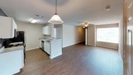 This single-floor residential unit offers a well-designed, functional layout with a seamless flow between living spaces. The open-concept kitchen and living area serves as the heart of the home, featuring rich hardwood-style flooring throughout. The kitchen is equipped with stainless steel appliances, including a refrigerator, electric range, and over-the-range microwave, complemented by ample white cabinetry, laminate countertops, and a peninsula that separates the kitchen from the living space. A stylish pendant light hangs above the peninsula, while a ceiling fan provides comfort in the adjoining living area, which benefits from natural light through a window.

The bedrooms are carpeted for warmth and comfort, each outfitted with ceiling fans and generous closet space, including a walk-in closet in at least one room. The bathrooms feature hardwood-style flooring, white vanity cabinetry, laminate countertops, large mirrors with overhead lighting, and practical fixtures. One bathroom provides direct access to an adjacent bedroom, enhancing convenience.

Throughout the unit, neutral wall tones create a clean, versatile backdrop, while white trim and doors add a crisp, cohesive finish. The layout is practical and well-proportioned, offering comfortable living across all areas of the home.