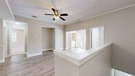 This single-floor residence in Jacksonville, Florida offers a thoughtfully designed layout with clean, contemporary finishes throughout. The open living area features warm-toned wood-look flooring, crown molding, and a ceiling fan with light fixture, creating a comfortable and well-lit atmosphere. A half-wall partition defines the space, seamlessly connecting the living area to the kitchen and adjoining rooms.

The kitchen is outfitted with white cabinetry, granite countertops, a stainless steel appliance suite including a range and microwave, a built-in dishwasher, and a single-basin sink. A louvered pantry door adds practical storage to this efficient galley-style layout.

The bedroom is generously proportioned, with soft carpeting underfoot, a ceiling fan, and a sliding glass door that opens to a private balcony overlooking lush outdoor greenery. Natural light fills the room through both the balcony door and an additional window. The walk-in closet offers wire shelving with dual hanging rods for organized storage.

The bathroom features wood-look flooring, a granite-topped vanity with white cabinetry, and a full tub-shower combination with chrome fixtures. Additional rooms include a versatile secondary space with chair-rail molding and in-unit laundry access. The overall palette of warm neutral tones lends the home a clean, move-in-ready appeal.