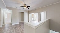 This single-floor residence in Jacksonville, Florida offers a thoughtfully designed layout with clean, contemporary finishes throughout. The open living area features warm-toned wood-look flooring, crown molding, and a ceiling fan with light fixture, creating a comfortable and well-lit atmosphere. A half-wall partition defines the space, seamlessly connecting the living area to the kitchen and adjoining rooms.

The kitchen is outfitted with white cabinetry, granite countertops, a stainless steel appliance suite including a range and microwave, a built-in dishwasher, and a single-basin sink. A louvered pantry door adds practical storage to this efficient galley-style layout.

The bedroom is generously proportioned, with soft carpeting underfoot, a ceiling fan, and a sliding glass door that opens to a private balcony overlooking lush outdoor greenery. Natural light fills the room through both the balcony door and an additional window. The walk-in closet offers wire shelving with dual hanging rods for organized storage.

The bathroom features wood-look flooring, a granite-topped vanity with white cabinetry, and a full tub-shower combination with chrome fixtures. Additional rooms include a versatile secondary space with chair-rail molding and in-unit laundry access. The overall palette of warm neutral tones lends the home a clean, move-in-ready appeal.