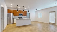 Located at 4622 Island Shores Ln in Lakeland, Florida, this single-story, 2-bedroom, 2-bathroom home offers a thoughtfully designed layout with modern finishes throughout. The open-concept kitchen and living area serves as the heart of the home, featuring light hardwood-style flooring, clean white walls, and abundant natural light from windows and a glass-paneled exterior door. The kitchen is well-appointed with warm wood cabinetry, granite countertops, stainless steel appliances including a refrigerator, range, and microwave, and a peninsula island with an integrated sink, ideal for both meal prep and casual dining. Pendant lighting and recessed fixtures illuminate the space effectively. The living area is complemented by a track lighting system and provides a comfortable, open atmosphere. Both bedrooms are carpeted and include ceiling fans, with the primary bedroom offering access to a spacious walk-in closet with wire shelving and a dedicated laundry room housing a full-size washer and dryer. The bathrooms feature granite-topped vanities, light hardwood-style flooring, and clean white tub-shower combinations with matte black fixtures, maintaining the home's cohesive modern aesthetic throughout.