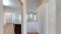 Located at 1810 Arden Creek Pl in Charlottesville, VA, this one-bedroom, one-bathroom residence offers a well-designed single-floor layout with a thoughtful mix of finishes and functional spaces. The living area is carpeted and filled with natural light from multiple windows, complemented by crown molding, a ceiling fan, and a ceiling-mounted track lighting fixture. A private exterior door provides direct outdoor access, adding convenience and openness to the space. The galley-style kitchen is a standout feature, showcasing rich dark wood cabinetry, granite countertops, hardwood flooring, stainless steel appliances including a refrigerator, microwave, and electric range, as well as a double stainless steel sink with pendant lighting overhead. A built-in desk area with matching granite countertop adds a practical workspace within the kitchen. The bedroom is a comfortable, carpeted retreat with a large window overlooking the outdoors. The full bathroom includes a dark wood vanity with a countertop sink, a tub-shower combination with tile surround, and tile flooring. A dedicated laundry room houses a full-size side-by-side washer and dryer with overhead shelving. A hallway closet provides additional storage, completing this efficiently organized home.