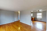 Located at 22 Revere Dr in Bloomfield, CT, this single-floor, 2-bedroom, 1-bathroom unit offers a comfortable and practical layout. Warm-toned hardwood floors run throughout the living spaces, adding character and continuity from room to room. The living room is an open, well-proportioned space with neutral gray walls and a ceiling fan, flowing naturally into the kitchen area. The kitchen features warm wood cabinetry, a peninsula, tile flooring, and a window that brings in natural light. Both bedrooms are generously sized with the same polished hardwood floors, gray walls, and louvered bi-fold closet doors. The primary bedroom includes a large window with outdoor views of the surrounding landscape, along with a wall-mounted AC unit and baseboard heating. The second bedroom also benefits from natural light through a wide multi-pane window overlooking greenery. The full bathroom is clean and functional, featuring white tile floors, white tile surround around the tub, a wood vanity with a single sink, and a window for ventilation. A hallway connects the rooms efficiently, and a dedicated closet provides additional storage. The unit is serviced by baseboard heating throughout.
