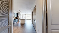 This thoughtfully designed 2-bedroom, 2-bathroom residence occupies a single floor and offers an open, flowing layout that maximizes comfort and functionality. The heart of the home is a spacious kitchen and living area featuring rich dark cabinetry contrasted by a large white quartz-topped island with an integrated sink, complemented by stainless steel appliances and a stylish tile backsplash. Pendant lighting and track lighting illuminate the space, while wide-plank hardwood-style flooring extends throughout the main living areas. The living room benefits from an abundance of natural light, with large windows and a glass door that frame outdoor views and create an airy, open ambiance. A ceiling fan adds to the comfort of the space. The primary bedroom is generously sized, featuring plush carpeting, a ceiling fan, and a large window that invites natural light. It connects to a well-equipped walk-in closet with dual hanging rods and built-in shelving on all sides. The primary bathroom is spacious and refined, offering a dual-sink vanity with dark cabinetry, large-format tile flooring, a glass-enclosed walk-in shower, and a soaking tub. A dedicated laundry room houses a full-sized washer and dryer with overhead shelving for added storage. Two closets provide ample organizational space throughout the residence.