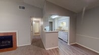 This single-floor residence offers a thoughtfully laid-out living space designed for comfort and functionality. The living room serves as the heart of the home, featuring a tile-surround fireplace, plush carpeting, a ceiling fan, vaulted ceilings with a textured finish, and a sliding glass door with vertical blinds that opens to an outdoor area, allowing natural light to fill the room. The front entryway flows seamlessly into this open living space, reinforcing the airy, welcoming atmosphere.

The kitchen is efficiently designed with white cabinetry, light countertops, a double-basin sink, and white appliances including a range, refrigerator, microwave, and dishwasher. Wood-look flooring runs through the kitchen, which also features a pass-through counter opening toward the living and dining area. A hallway off the main living space leads to the private quarters of the home.

The bedrooms are carpeted and well-proportioned, each featuring windows with blinds that bring in natural light. One bedroom is equipped with a ceiling fan, while the other offers a flush-mount light fixture. The bathrooms include a vanity with ample counter space and storage, a full bathtub with a shower, and wood-look flooring, providing a clean and practical finish throughout.