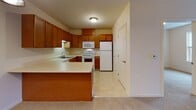 Located at 1880 Sweet Home Rd in Buffalo, NY, this single-floor unit offers a thoughtfully designed layout with a range of functional spaces. The kitchen is equipped with warm honey-toned wood cabinetry, light countertops, and a full suite of white appliances including an electric range, over-the-range microwave, dishwasher, and refrigerator. A peninsula countertop extends the workspace and provides a natural transition into the adjacent living and dining area. The dining space features an elegant chandelier and connects seamlessly to the rest of the unit. The living area is carpeted and filled with natural light, opening through French doors to a private balcony — a standout feature that extends the living space outdoors. The bedrooms are carpeted and well-lit, each with windows that allow ample natural light; one overlooks the surrounding neighborhood. The bathroom includes a single-sink vanity with wood cabinetry, a large mirror, and a glass-enclosed shower stall with chrome fixtures. Throughout the unit, neutral tones, clean lines, and consistent finishes create a cohesive and comfortable atmosphere suited for everyday living.