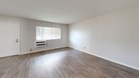 Located at 5800 South St in Lakewood, California, this two-bedroom, one-bathroom single-floor unit offers a clean, contemporary layout designed for comfortable everyday living. The open-concept kitchen and living area serves as the heart of the home, featuring sleek white cabinetry, stainless steel appliances including a gas range, microwave, and refrigerator, as well as light-toned wood-look flooring and a skylight that fills the space with natural light. A peninsula counter provides additional prep space and a natural division between the kitchen and living area. The living room is bright and airy, with a large window fitted with horizontal blinds, a wall-mounted air conditioning unit, and wood-look flooring that adds warmth to the neutral palette. Both bedrooms continue the wood-look flooring and are finished with light gray walls, generous windows for natural light, and ceiling fans for year-round comfort. The primary bedroom offers a comfortable footprint with ample room for furnishings. The full bathroom is neatly appointed with a white vanity, a combined tub and shower, and matching wood-look tile flooring. A hallway and closet round out the thoughtfully organized floor plan, making efficient use of the available space throughout.