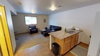 This multi-level home spans three floors and offers four bedrooms and three and a half bathrooms, providing ample space for residents and guests alike. The layout is thoughtfully distributed across the floors, delivering both private and communal areas suited to a variety of living arrangements. The lower level features an open living area with carpeted and tiled flooring, where a kitchenette with warm wood cabinetry, a double-basin sink, and a peninsula counter connects seamlessly to a comfortable lounge space. A window brings in natural light, brightening the room and creating a welcoming atmosphere. The neutral color palette of light gray and white walls throughout lends the home a clean, understated aesthetic. Ceiling-mounted lighting fixtures provide consistent illumination across the living spaces. The home's multi-floor design allows for clear separation between living, sleeping, and utility areas, making it a practical and versatile residence. With its combination of bedroom count, bathroom access, and spread-out floor plan, this property offers a well-rounded living environment with room to accommodate diverse needs.