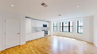 Located in Washington, DC's vibrant Adams Morgan neighborhood, this well-designed 1-bedroom residence offers a thoughtfully arranged single-floor layout. The open-plan kitchen and living area serves as the heart of the space, featuring warm hardwood floors that extend throughout, crisp white walls, and recessed lighting. The kitchen is outfitted with sleek, handle-free white cabinetry extending to the ceiling, stainless steel appliances including a gas range with oven and built-in microwave, and a streamlined sink — all seamlessly integrated into the living area. Large, grid-paned windows with dark frames line the living and bedroom spaces, flooding the interior with abundant natural light and providing views of the surrounding neighborhood. The spacious bedroom accommodates a generous footprint and continues the warm hardwood flooring and bright, neutral palette. A dedicated closet provides practical storage. The bathroom presents a clean, modern aesthetic with large-format neutral tiles, a glass-enclosed walk-in shower with rainfall fixture, a wall-mounted vanity with ample drawer storage, and a sleek toilet. A hallway connects the main living areas, completing this well-appointed urban residence.