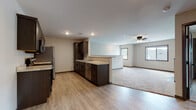 This single-floor home is designed with a practical and modern layout that emphasizes open living. The kitchen is a standout feature, outfitted with dark espresso cabinetry, light granite-style countertops, and a full suite of stainless steel appliances including a range, microwave, refrigerator, and dishwasher. Light wood-look flooring runs throughout the kitchen and flows into the adjoining dining and transitional areas, creating a cohesive, clean aesthetic. A peninsula with countertop seating connects the kitchen to the living space, enhancing the open-concept feel.

The living room is generously sized, finished with plush carpet, a ceiling fan, and a tiled electric fireplace that serves as a focal point. Multiple windows allow natural light to fill the space, offering views of the surrounding neighborhood. Bedrooms are carpeted and equipped with ceiling fans, with windows that bring in additional daylight.

The bathroom features a full soaking tub and shower combination with clean white surround and wood-look flooring. A dedicated laundry room houses a full-size Samsung washer and dryer with overhead wire shelving, adding everyday convenience to this well-appointed home.