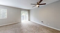 Located at 3811 NE Third Ct in Renton, WA, this efficiently designed single-floor unit offers a well-organized layout comprising a living room, kitchen, bathroom, and hallway. The living room serves as the central gathering space, finished with plush wall-to-wall carpeting and neutral gray walls that create a clean, inviting atmosphere. A ceiling fan with integrated lighting provides both comfort and illumination, while large sliding glass doors dressed with vertical blinds flood the room with natural light and offer views of the surrounding greenery. The galley-style kitchen is thoughtfully appointed with white shaker cabinetry, white countertops, and wood-look vinyl flooring. Stainless steel appliances — including a refrigerator, electric range with overhead exhaust hood, and a single-basin sink — lend a modern, functional character to the space. The hallway provides access to the bathroom and features mirrored sliding closet doors, maximizing both storage and the sense of space. The bathroom is outfitted with a tub-shower combination with a white surround, a toilet, and textured walls that add subtle visual interest. Throughout the unit, consistent neutral tones and practical finishes contribute to a cohesive, move-in-ready aesthetic.