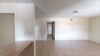 Located at 4848 East Holly Street in Phoenix, Arizona, this single-story, 2-bedroom, 1-bathroom residence offers a practical and well-organized layout. Tile flooring runs consistently throughout the home, lending a cohesive, easy-to-maintain finish to every room. The interior is bathed in neutral tones with textured ceilings adding dimension overhead.

The entrance leads into a combined living and dining area, where sliding glass doors fitted with vertical blinds open to a private balcony, bringing in natural light and outdoor greenery views. The galley-style kitchen is accessible via an arched opening and features warm wood cabinetry lining both walls, a white range and refrigerator, and a window that provides additional natural light.

Two bedrooms are connected via a hallway, each offering a comfortable footprint. The primary bedroom is notably spacious and also benefits from sliding door access to the balcony. Both bedrooms include closets, providing ample storage. The full bathroom includes a tub-shower combination, toilet, and vanity with wood cabinetry. Two hallways connect the various spaces efficiently, contributing to a smooth flow throughout the home. Overall, the residence presents a clean, functional living environment suited for everyday comfort.