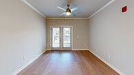 Located at 4415 Percival Rd in Columbia, SC, this well-appointed 2-bedroom, 2-bathroom single-story home offers a thoughtfully designed layout with modern finishes throughout. Warm hardwood-style flooring flows consistently across the entire space, complemented by clean white baseboards and crown molding that add a polished touch to every room.

The kitchen serves as the centerpiece of the home, featuring crisp white shaker cabinets, a subway tile backsplash, stainless steel appliances—including a French door refrigerator, electric range, and built-in microwave—and a spacious center island with a white quartz countertop, undermount sink, and pendant lighting above. Recessed lighting and crown molding complete the kitchen's refined look.

The living area is bright and open, with a ceiling fan and double glass doors that invite natural light and provide outdoor access. Both bedrooms are comfortably sized, each with a ceiling fan and windows fitted with blinds for privacy and light control. The primary bedroom includes a dedicated closet with wire shelving for organized storage.

The two bathrooms are cleanly finished: the primary bath features a glass-enclosed walk-in shower, while the secondary bath offers a full tub-shower combination with a white vanity and matching cabinetry. The overall aesthetic is neutral, modern, and move-in ready.