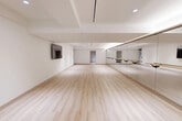 Located at 1575 Queen St E in Toronto's vibrant east end, this purpose-built dance and fitness studio offers a clean, modern environment designed for movement and performance. The single-floor space is thoughtfully laid out to maximize open floor area, providing ample room for classes, rehearsals, or training sessions.

The main studio is the centerpiece of the space, featuring a full-length mirrored wall fitted with wall-mounted wooden ballet barres at two heights — ideal for dance training and barre fitness classes. Light-toned hardwood flooring runs throughout, offering both aesthetic warmth and a practical, supportive surface underfoot. Recessed ceiling lighting provides consistent, even illumination across the entire floor area, complemented by subtle cove lighting along the mirror wall.

A wall-mounted flat-screen television is positioned opposite the mirror wall, supporting instructional or multimedia use. Built-in open shelving along one end of the studio offers convenient storage for equipment or personal belongings.

The entry area features an automatic, accessibility-compliant door with smooth light hardwood flooring that flows seamlessly into the studio. The crisp white walls and clean architectural lines throughout create a bright, focused atmosphere well-suited to a professional fitness or dance environment.
