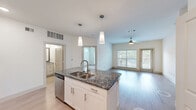 Located at 133 Foremost Dr in Austin, TX, this single-story residence offers a thoughtfully designed open-concept floor plan with two bedrooms and two full bathrooms. The kitchen serves as a focal point of the home, showcasing a large center island with dark granite countertops, an undermount sink, pendant lighting, white shaker-style cabinetry, a tile backsplash, and stainless steel appliances including a refrigerator, range, microwave, and dishwasher. The kitchen flows seamlessly into the living area, which features wood-style flooring, a ceiling fan, and large windows alongside a glass door that invite abundant natural light and views of the outdoors. The primary bedroom is a comfortable retreat with plush carpet, a natural light window, and access to a spacious walk-in closet. The second bedroom also features carpet flooring. Both bathrooms are finished with granite-topped white vanities and wood-look tile flooring; one bathroom includes a tiled tub-shower combination, while the other features a single vanity with cabinet storage. Additional closets provide ample storage throughout the home. The clean, neutral color palette and consistent finishes create a cohesive and move-in-ready living environment.