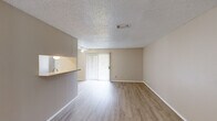 This single-floor residence offers a practical and well-organized layout across two bedrooms and two bathrooms. The combined kitchen and living area forms the heart of the home, where light wood-look flooring, neutral beige walls, and a textured ceiling create a clean, understated aesthetic. A ceiling fan adds functionality, while a sliding glass door fitted with vertical blinds fills the living space with natural light and provides access to the outdoors.

The galley-style kitchen is efficiently arranged with white cabinetry lining both walls, offering ample storage above and below the countertops. White appliances — including a refrigerator, electric range, and dishwasher — are neatly integrated, and a pass-through counter connects the kitchen to the living area.

Both bedrooms are comfortably sized, with the primary bedroom offering a generous footprint, a ceiling fan with light fixture, and direct access to a dedicated closet. The second bedroom also features wood-look flooring and neutral walls. Each bedroom is served by its own closet, with one featuring built-in shelving and hanging rods for organized storage.

The two bathrooms are functional and straightforward, each featuring a tub-shower combination with white tile surrounds and wood-look flooring. The overall ambiance of the residence is clean, neutral, and move-in ready.