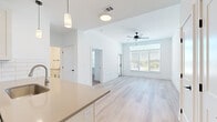 Located at 760 NW Shoal Creek Parkway in Kansas City, MO, this thoughtfully designed three-bedroom, two-bathroom residence offers a clean, contemporary aesthetic across its two floors. The open-concept kitchen and living area serves as the heart of the home, featuring light hardwood-style flooring, white shaker cabinetry, a subway tile backsplash, stainless steel appliances, and a peninsula with pendant lighting overhead. The living room benefits from oversized windows and a ceiling fan, with a private balcony accessible through a glass door that frames outdoor views.

The primary bedroom is generously sized, bathed in natural light from large windows, and finished with light hardwood-style flooring and a ceiling fan. It includes a walk-in closet outfitted with wire shelving for organized storage. The two additional bedrooms feature plush carpeting, ceiling fans, and bright windows, making them well-suited for various uses. Both bathrooms are finished with white cabinetry featuring matte black hardware, quartz-style countertops, and a clean, neutral palette. The full bath includes a tub-shower combo. Throughout the home, crisp white walls, consistent flooring choices, and black hardware accents create a cohesive and modern feel.