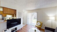 This 1-bedroom, 1-bathroom unit offers a thoughtfully arranged single-floor layout that makes efficient use of every square foot. The living room features warm hardwood-style flooring, a textured ceiling, and a sliding glass door fitted with vertical blinds that floods the space with natural light and provides access to an outdoor area. The open sightline connects the living room to the kitchen, which is equipped with wood-toned cabinetry, a white refrigerator, and a range, complemented by a pass-through counter that enhances the sense of openness. Adjacent to the kitchen, a dedicated dining nook features chair rail molding, decorative wall art, and a pendant light overhead, creating an inviting area for meals. The bedroom is a quiet retreat with plush carpet flooring, a ceiling fan with light, a window with blinds for natural light, and ample wall space. The bathroom includes a single-sink vanity with warm wood cabinetry, overhead lighting, a large mirror, and a shower-tub combination with a curtain. Throughout the unit, neutral wall tones and consistent finishes contribute to a clean, cohesive aesthetic well-suited for comfortable everyday living.