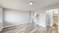 Located at 11440 Old River School Rd in Downey, CA, this thoughtfully designed single-floor unit offers an efficient and modern living experience. The interior is unified by light gray laminate wood-style flooring that runs throughout, complemented by soft gray-blue walls and crisp white trim, creating a clean and contemporary aesthetic.

The spacious living room serves as the heart of the unit, featuring large windows with horizontal blinds that invite natural light while maintaining privacy. The open layout provides a welcoming and versatile space with a front entry door that connects directly to the room.

The kitchen is a standout feature, offering white shaker-style cabinetry extending to the ceiling for ample storage, stainless steel appliances including a refrigerator, gas range, and microwave, and a mosaic tile backsplash in neutral tones that adds visual interest. A stainless steel sink sits beneath a window overlooking the outdoors, and light quartz-style countertops complete the polished look.

The bathroom is equally refined, featuring a tub and shower combination enclosed by sliding frosted glass doors, marble-look tile surrounds with mosaic accent detailing, and a white vanity with a clean countertop. Every room reflects a cohesive, updated design that balances functionality with modern style.