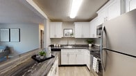 Located at 1399 Phillips Rd in New Bedford, Massachusetts, this single-floor residence offers a thoughtfully designed layout that balances comfort and functionality. The kitchen is a standout feature, showcasing white shaker-style cabinetry, dark granite-look countertops, light wood-look flooring, and a full suite of stainless steel appliances including a refrigerator, range, microwave, and dishwasher. Ample cabinet storage and a deep undermount sink make this kitchen both practical and visually appealing. The living area is generously sized, featuring plush wall-to-wall carpeting and a sliding glass door that opens to a private balcony, allowing natural light to fill the space and providing views of surrounding greenery. A coat closet near the entryway adds convenient storage. The bedroom is comfortably proportioned, also finished with soft carpeting, and features a window with vertical blinds that frame natural outdoor views. The bathroom is clean and efficiently laid out, with a white vanity topped with a dark countertop, a full tub-shower combination, and light wood-look flooring that ties the space together. A textured ceiling is consistent throughout the unit. Overall, this residence offers a clean, modern aesthetic with practical finishes suited for comfortable everyday living.