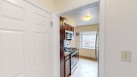 This single-floor residence offers a practical and comfortable layout across three bedrooms, one bathroom, a living room, kitchen, and hallway. The kitchen is a standout feature, outfitted with rich dark-wood cabinetry, granite countertops, a decorative tile backsplash, stainless steel appliances including a dishwasher, range, and refrigerator, and light ceramic tile flooring. A window above the sink allows natural light to fill the space. The three bedrooms are carpeted and finished with neutral tones, providing a warm and restful atmosphere. Each room benefits from natural light through well-sized windows that offer exterior views of the surrounding neighborhood. The primary bedroom includes a built-in closet with shelving and hanging storage. The full bathroom is tiled throughout, featuring a soaking tub with a tiled surround accented by a mosaic tile border, along with a vanity and a window for added ventilation and light. The hallway connects the rooms efficiently, contributing to the cohesive single-level flow of the home. Overall, the space presents a clean, functional design with consistent finishes throughout, making it a well-structured and move-in ready residence.
