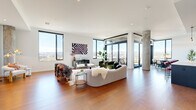 This spacious Denver residence offers an impressive single-floor layout with 3 bedrooms and 5 bathrooms, designed with a sleek contemporary aesthetic. The open-concept living area is anchored by rich hardwood flooring, exposed concrete columns, and floor-to-ceiling windows that flood the space with natural light and frame breathtaking panoramic views of the Denver skyline and Rocky Mountains. A generous dining area sits adjacent to a glass-enclosed balcony, perfect for taking in the cityscape. The chef's kitchen features dark flat-front cabinetry reaching full ceiling height, stainless steel appliances, a white quartz island, and a striking gold faucet. The spacious primary bedroom offers direct balcony access through wide glass doors and is complemented by a large walk-in closet with custom built-in shelving. The bathrooms are elegantly appointed with marble-look tile flooring, floating wood vanities, white quartz countertops, gold fixtures, and bold teal accent tile. Clean white hallways with hardwood flooring connect the private quarters. A dedicated in-unit laundry room adds everyday convenience. Throughout, the home balances modern sophistication with warm, livable design in a high-rise setting above Denver.