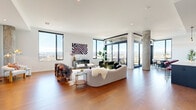 This spacious Denver residence offers an impressive single-floor layout with 3 bedrooms and 5 bathrooms, designed with a sleek contemporary aesthetic. The open-concept living area is anchored by rich hardwood flooring, exposed concrete columns, and floor-to-ceiling windows that flood the space with natural light and frame breathtaking panoramic views of the Denver skyline and Rocky Mountains. A generous dining area sits adjacent to a glass-enclosed balcony, perfect for taking in the cityscape. The chef's kitchen features dark flat-front cabinetry reaching full ceiling height, stainless steel appliances, a white quartz island, and a striking gold faucet. The spacious primary bedroom offers direct balcony access through wide glass doors and is complemented by a large walk-in closet with custom built-in shelving. The bathrooms are elegantly appointed with marble-look tile flooring, floating wood vanities, white quartz countertops, gold fixtures, and bold teal accent tile. Clean white hallways with hardwood flooring connect the private quarters. A dedicated in-unit laundry room adds everyday convenience. Throughout, the home balances modern sophistication with warm, livable design in a high-rise setting above Denver.