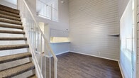 Located at 2167 NE Loop 410 in San Antonio, TX, this two-story residence offers 2 bedrooms and 2 bathrooms spread across two floors. The main level serves as the primary living area, featuring distinctive shiplap wall paneling and rich, dark hardwood-style flooring that lends a modern yet warm character to the space. A sleek white staircase with open metal railings connects the two floors, serving as a visual centerpiece while allowing light to flow freely throughout. The upper level continues the shiplap aesthetic and includes a small window that brings in natural light, adding to the airy feel of the upper space. Both bedrooms are carpeted for comfort and feature neutral toned walls and windows with outdoor views, allowing natural light to fill each room. The spacious primary bedroom includes a ceiling fan with integrated lighting. Each of the two bathrooms is clean and functional, equipped with a tub-shower combination, wood-style flooring, and bright white tilework. One bathroom features a vanity with white cabinetry. A dedicated closet and hallway provide additional storage and connectivity throughout the layout, making this a well-organized and efficient two-story home.