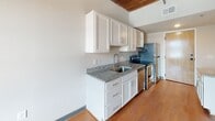 Located at 12 S 17th St in Richmond, VA, this single-floor unit masterfully combines historic industrial character with contemporary updates. The living area is defined by striking exposed brick walls, original heavy timber wood-beam ceilings, and warm hardwood flooring that together create an authentic loft-style ambiance. Large windows set within the brick allow natural light to fill the space while offering views of the surrounding Shockoe Bottom neighborhood.

The kitchen features white shaker-style cabinetry, granite countertops, a stainless steel sink, and a full suite of stainless steel appliances including a refrigerator, electric range, and dishwasher. Hardwood flooring continues throughout the kitchen, which also includes a louvered-door closet for additional storage.

The bedroom continues the building's historic character with exposed brick, wood-beam ceilings, and a large arched window, while plush carpeting underfoot adds comfort. Two bathrooms serve the unit: one features a granite-topped vanity with an LED-framed mirror and a stacked in-unit washer/dryer, while the second offers a full soaking tub with shower. Clean white walls throughout provide a bright, modern contrast to the rich historic architectural details.