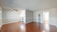 Located at 14630 Saticoy St in Los Angeles, CA, this 1-bedroom, 2-bathroom unit offers a practical and comfortable single-floor layout. The open-concept living and dining area is a standout feature, showcasing rich, warm-toned hardwood flooring that flows throughout the main living spaces. Neutral gray walls with white chair-rail molding provide a clean, modern aesthetic, while a ceiling fan adds functionality. Large windows allow natural light to fill the room, creating a bright and welcoming ambiance. The kitchen is efficiently designed with white cabinetry, a gas range, and ample counter space, and is open to the main living area for a connected feel. The spacious primary bedroom is finished with plush carpet, a ceiling fan, a window with an outdoor view, and a full-width sliding closet for generous storage. A second closet provides additional storage elsewhere in the unit. Two bathrooms serve the space, one featuring a full tub/shower combination with a window above and hardwood-style flooring. A textured ceiling is consistent throughout the unit, adding a classic touch to this well-maintained Los Angeles residence.