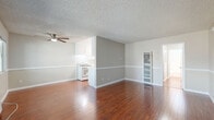 Located at 14630 Saticoy St in Los Angeles, CA, this 1-bedroom, 2-bathroom unit offers a practical and comfortable single-floor layout. The open-concept living and dining area is a standout feature, showcasing rich, warm-toned hardwood flooring that flows throughout the main living spaces. Neutral gray walls with white chair-rail molding provide a clean, modern aesthetic, while a ceiling fan adds functionality. Large windows allow natural light to fill the room, creating a bright and welcoming ambiance. The kitchen is efficiently designed with white cabinetry, a gas range, and ample counter space, and is open to the main living area for a connected feel. The spacious primary bedroom is finished with plush carpet, a ceiling fan, a window with an outdoor view, and a full-width sliding closet for generous storage. A second closet provides additional storage elsewhere in the unit. Two bathrooms serve the space, one featuring a full tub/shower combination with a window above and hardwood-style flooring. A textured ceiling is consistent throughout the unit, adding a classic touch to this well-maintained Los Angeles residence.