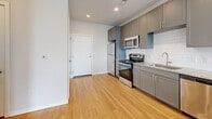 Located at 3165 S Quari St in Aurora, CO, this well-appointed one-bedroom, one-bathroom residence offers a thoughtfully designed single-floor layout. The open-concept living, dining, and kitchen area creates a bright, cohesive space ideal for everyday living and entertaining. The kitchen stands out with sleek gray shaker cabinetry, granite countertops, a classic white subway tile backsplash, stainless steel appliances including a range, microwave, and refrigerator, and warm hardwood-style flooring that flows throughout the main living area. Pendant lighting above the kitchen peninsula adds a modern touch, while large windows invite ample natural light into the living space. The bedroom features soft carpeting, generous closet space, and oversized windows that frame open outdoor views, flooding the room with sunlight. The full bathroom is clean and functional, offering a tub/shower combination with crisp white surrounds and hardwood-style flooring. Additional highlights include three closets for abundant storage and a dedicated in-unit laundry area for everyday convenience. The overall aesthetic is modern and neutral, with a cohesive color palette that creates a calm, welcoming ambiance throughout.