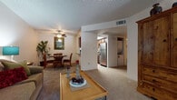 This single-floor residence offers a thoughtfully designed layout that seamlessly connects the main living areas. The living room provides a welcoming, open atmosphere, featuring plush carpeting, a ceiling fan, a textured ceiling, and a large window with vertical blinds that invite natural light while offering views of the outdoors. The space comfortably accommodates multiple seating arrangements, making it ideal for relaxing or entertaining.

Adjacent to the living room, the dining area offers an intimate setting highlighted by carpeted flooring, a ceiling fan, and a decorative framed mirror on the wall. A convenient pass-through counter connects the dining area directly to the kitchen, enhancing the flow between spaces.

The kitchen is efficiently laid out in a galley style, featuring rich dark cabinetry, dark granite-style countertops, light wood-look flooring, and stainless steel appliances including a refrigerator, electric range, over-the-range microwave, and dishwasher. An in-unit laundry area is conveniently located just off the kitchen.

The bedroom is a comfortable retreat, complete with carpeted flooring, a ceiling fan, and a window that brings in natural light. The bathroom features rich dark wood cabinetry paired with striking dark granite-style countertops, a large vanity mirror, and a shower-tub combination, all set on wood-look flooring for a cohesive, polished finish.