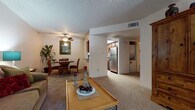 This single-floor residence offers a thoughtfully designed layout that seamlessly connects the main living areas. The living room provides a welcoming, open atmosphere, featuring plush carpeting, a ceiling fan, a textured ceiling, and a large window with vertical blinds that invite natural light while offering views of the outdoors. The space comfortably accommodates multiple seating arrangements, making it ideal for relaxing or entertaining.

Adjacent to the living room, the dining area offers an intimate setting highlighted by carpeted flooring, a ceiling fan, and a decorative framed mirror on the wall. A convenient pass-through counter connects the dining area directly to the kitchen, enhancing the flow between spaces.

The kitchen is efficiently laid out in a galley style, featuring rich dark cabinetry, dark granite-style countertops, light wood-look flooring, and stainless steel appliances including a refrigerator, electric range, over-the-range microwave, and dishwasher. An in-unit laundry area is conveniently located just off the kitchen.

The bedroom is a comfortable retreat, complete with carpeted flooring, a ceiling fan, and a window that brings in natural light. The bathroom features rich dark wood cabinetry paired with striking dark granite-style countertops, a large vanity mirror, and a shower-tub combination, all set on wood-look flooring for a cohesive, polished finish.
