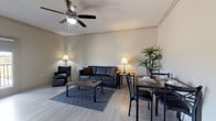 This single-floor residence offers a well-designed layout that maximizes its living space across one bedroom and one bathroom. The open-concept living and dining area is anchored by light wood-style flooring and neutral wall tones that create a clean, cohesive aesthetic. A ceiling fan overhead provides both function and a subtle design element. The living area accommodates a dark leather sofa and matching armchair arranged around a patterned area rug and coffee table, while a dedicated dining space features a dark metal-framed table with seating for multiple guests. A tall indoor plant adds a natural accent to the room.

The galley-style kitchen is efficiently organized with dark cabinetry, granite-style countertops, and stainless steel appliances, including a range and over-the-range microwave. Light flooring carries throughout, maintaining visual continuity across the space.

The bedroom is a calm, understated retreat featuring warm lamp lighting, a full-size bed with crisp white bedding, and a leather accent chair with ottoman positioned nearby. Matching nightstands flank the bed for a symmetrical, polished look.

The bathroom includes a full tub-and-shower combination with floor-to-ceiling gray tile surround, a dark vanity with granite countertop, and a framed mirror, delivering a clean and functional finish.