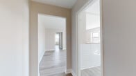 Located along Boulevard East in West New York, NJ, this single-floor unit has been thoughtfully renovated with contemporary finishes throughout. Light-toned hardwood-style flooring runs continuously across the space, creating a cohesive and clean aesthetic from room to room.

The entry foyer is compact yet functional, featuring an intercom system and crisp white trim. It opens into a spacious living area bathed in natural light, which flows seamlessly into the kitchen via a pass-through counter. The kitchen is well-appointed with white shaker cabinetry, stone countertops, a classic white subway tile backsplash, stainless steel appliances including a gas range and microwave, and a single-basin sink positioned beneath a window.

The bedrooms are generously sized, each featuring large windows that invite natural light and views of the surrounding neighborhood. Classic cast-iron radiators provide character alongside the modern updates. Neutral warm-toned walls complement the light flooring throughout.

The bathroom is finished with large-format beige floor and wall tiles, a soaking tub with a tiled surround, a floating white vanity, and brushed gold fixtures, lending a refined and timeless feel. A hallway connects the rooms efficiently, with a tiled bathroom glimpsed off to one side. Overall, the unit presents a clean, move-in-ready environment with a balance of classic building character and modern renovation.