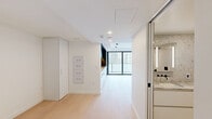 Located on the 15th floor at 300 Virginia St in the heart of Seattle, this thoughtfully designed studio offers a clean, contemporary aesthetic throughout. The open-plan living area is finished with light-toned wide-plank hardwood flooring that extends seamlessly across the space, complemented by crisp white walls and recessed lighting that create a bright, airy atmosphere. The integrated kitchen is a standout feature, showcasing a bold navy upper cabinet system with under-cabinet lighting, white lower cabinetry with a warm butcher block countertop, a gas cooktop, built-in wall oven, and a sleek matte black sink fixture. Floor-to-ceiling sliding glass doors open directly onto the private balcony, flooding the interior with natural light and framing impressive views of the Seattle skyline. The bathroom is elegantly appointed with terrazzo tile covering the floors and walls, white floating cabinetry, a wall-mounted toilet, and matte black fixtures and hardware throughout, lending a refined, spa-like quality. A smart home control panel is conveniently integrated into the living area wall. The unit's efficient layout and high-end finishes make it a compelling urban residence in one of Seattle's most vibrant neighborhoods.